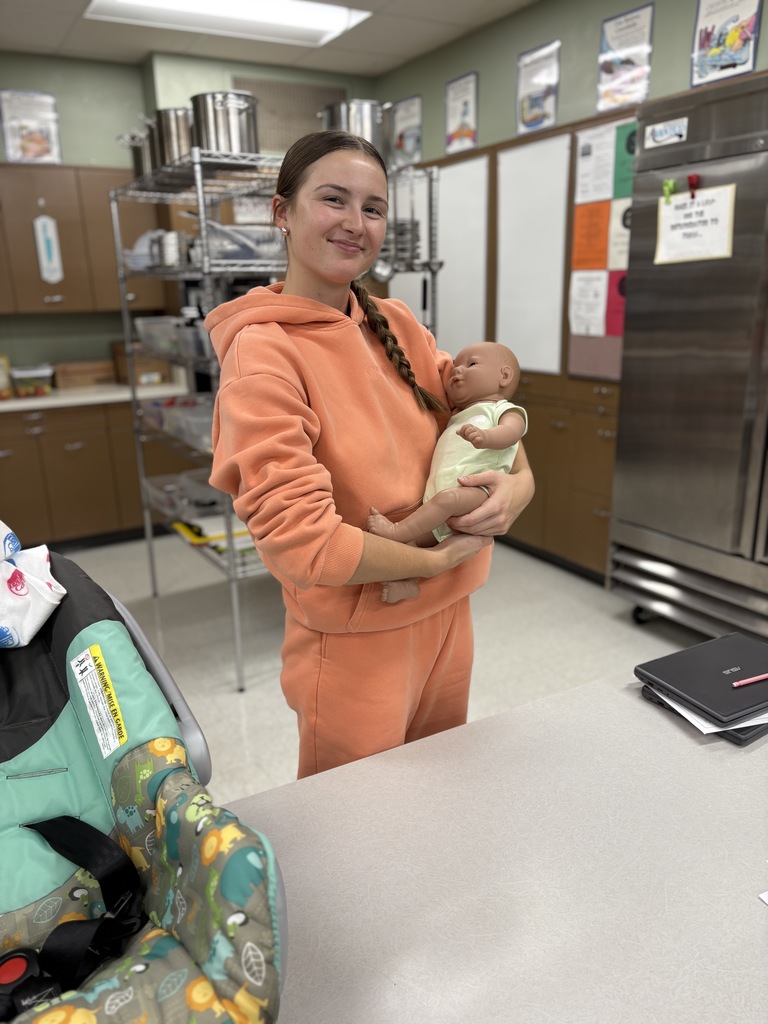 High school student practices holding a baby safely (using a doll).