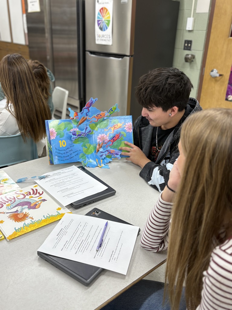 High school students practice reading a children's book out loud. 
