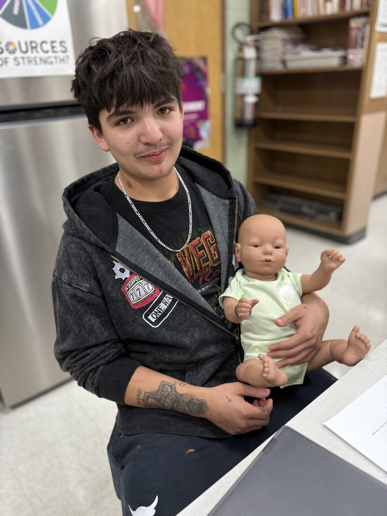 High school student practices holding a baby safely (using a doll).