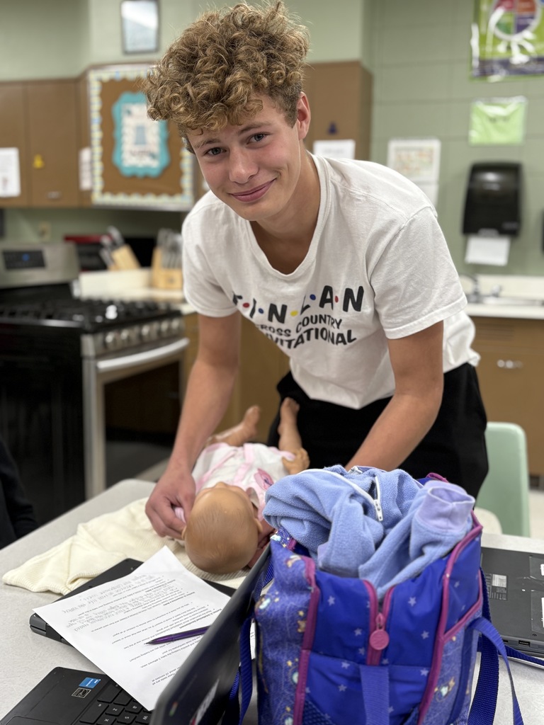 High school student practices getting a baby dressed (using a doll).