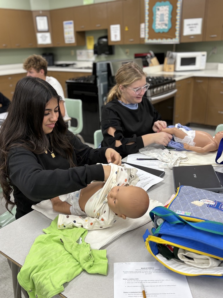 High school students practice getting a baby dressed (using dolls)