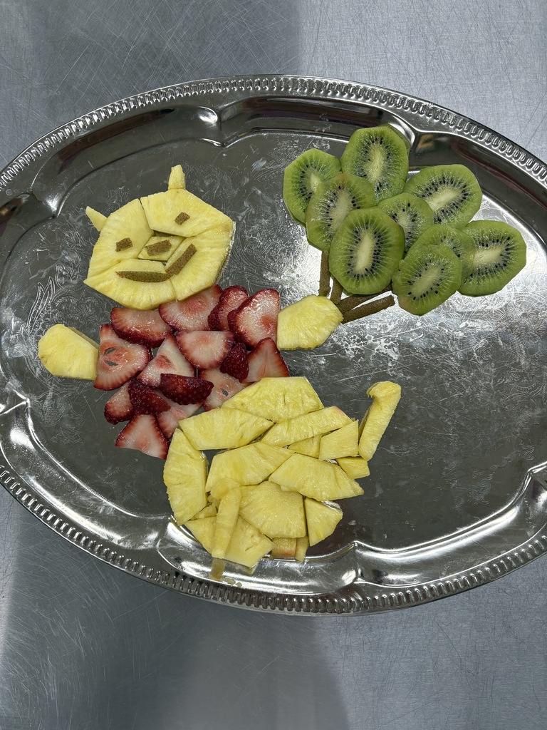 Fruit garnish shaped like an animal holding balloons.