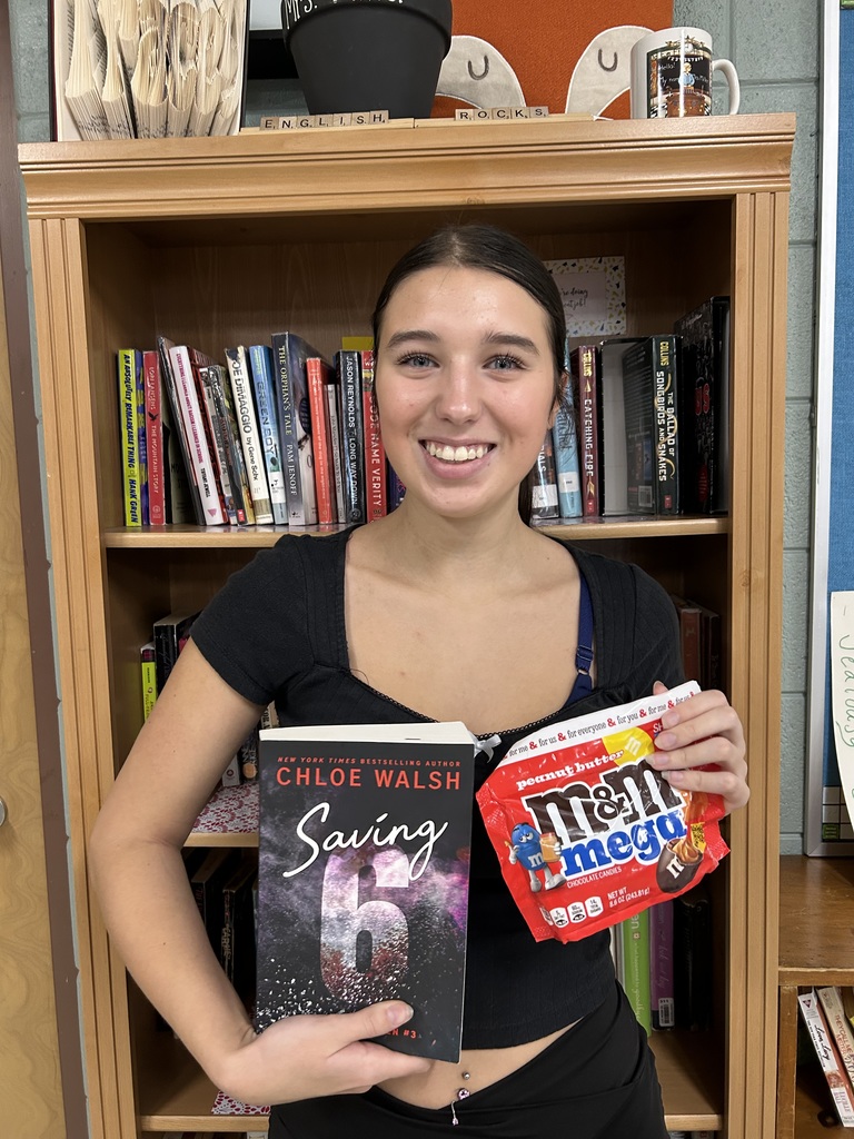 High school student standing holding a book and a treat.