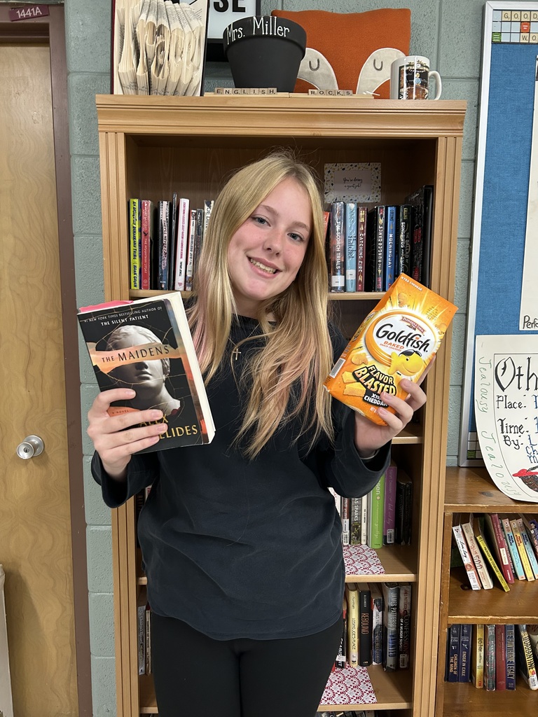 High school student standing holding a book and a treat.
