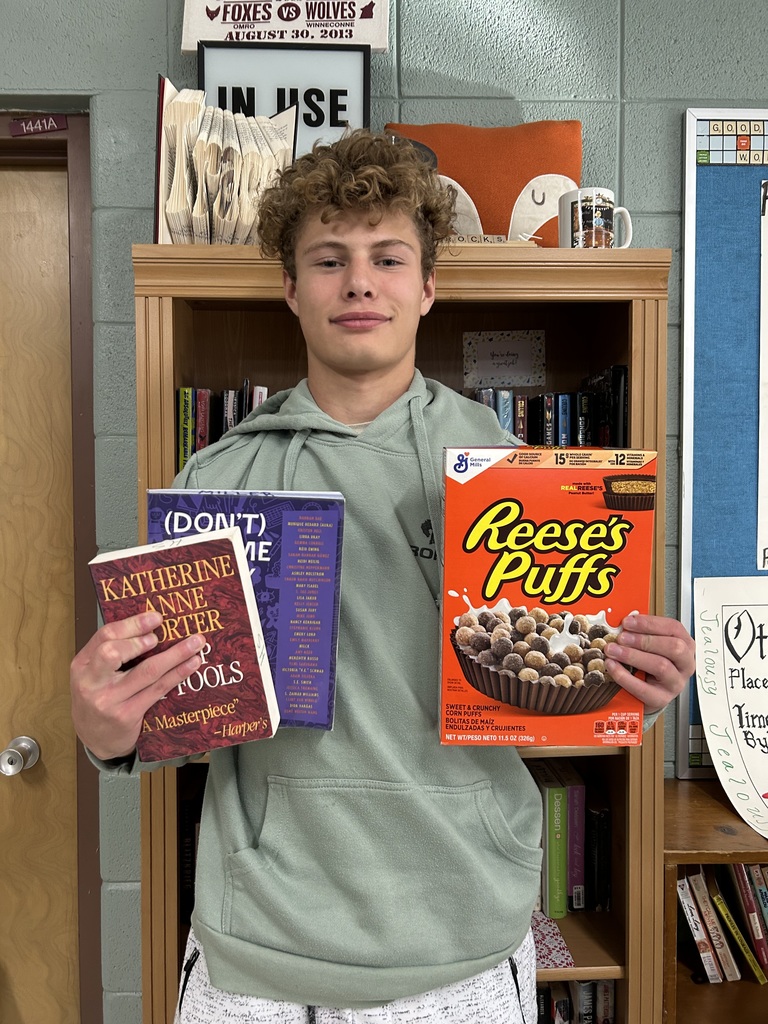 High school student standing holding a book and a treat.