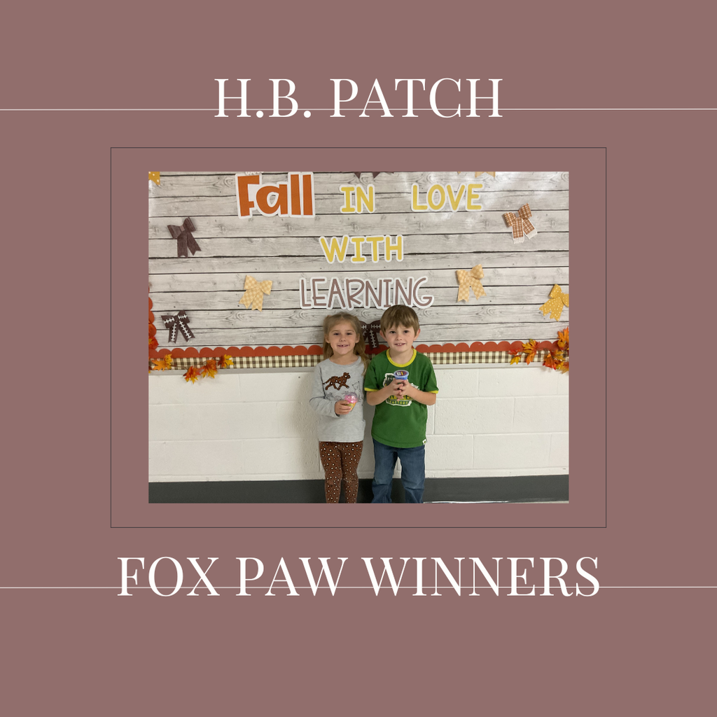 A couple of early elementary students standing in front of a bulletin board.