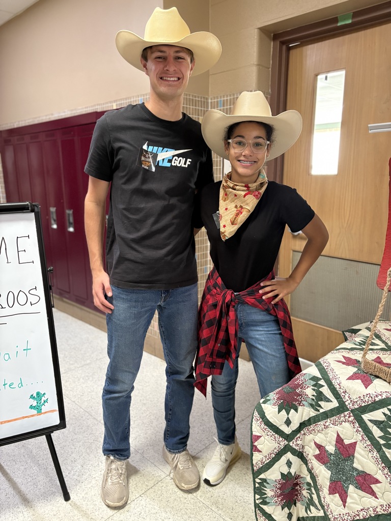 Two high school students standing together wearing cowboy hats.