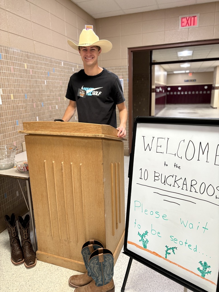 A high school student standing behind a podium, ready to greet people. 