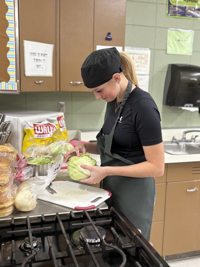 A high school student working with a head of lettuce. 