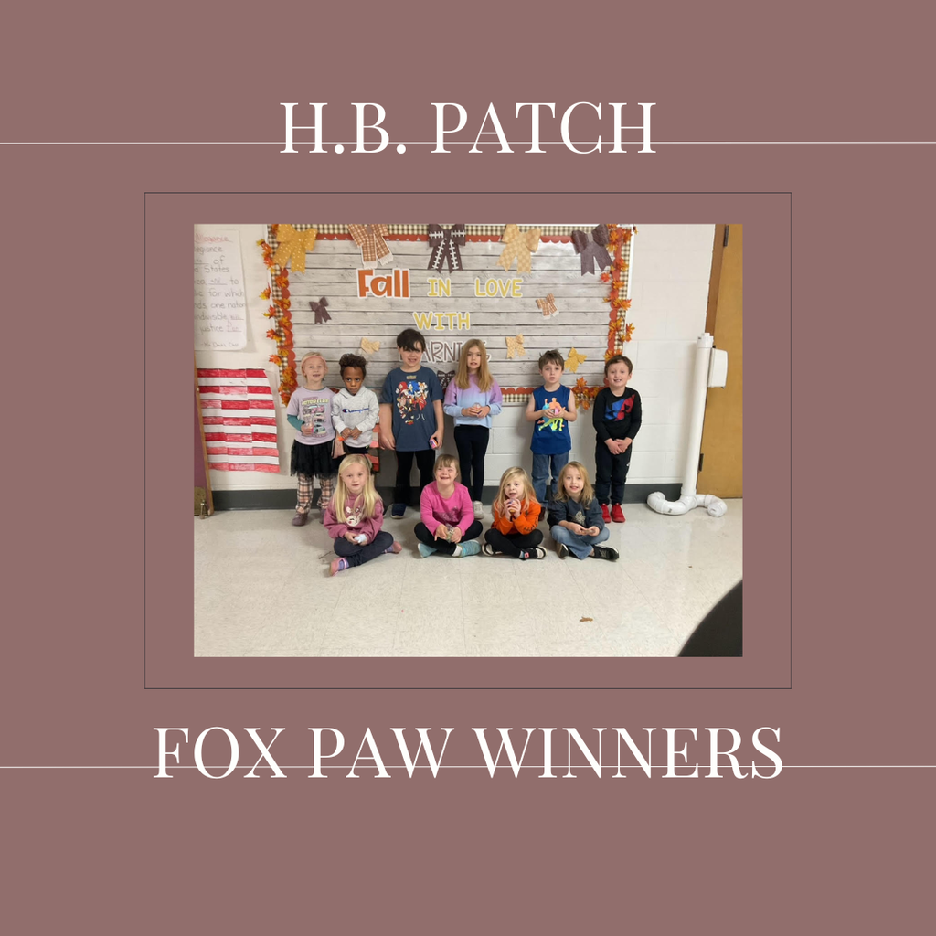 A group of early elementary students standing in front of a bulletin  board.