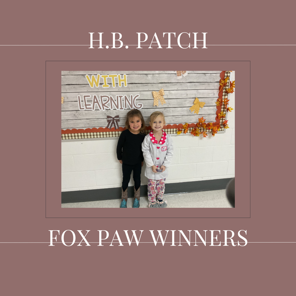 A couple of early elementary students standing in front of a bulletin board. 