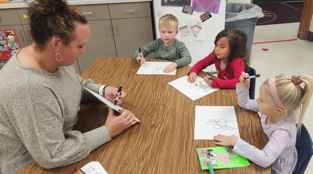Early elementary students working with a teacher on a directed drawing. 