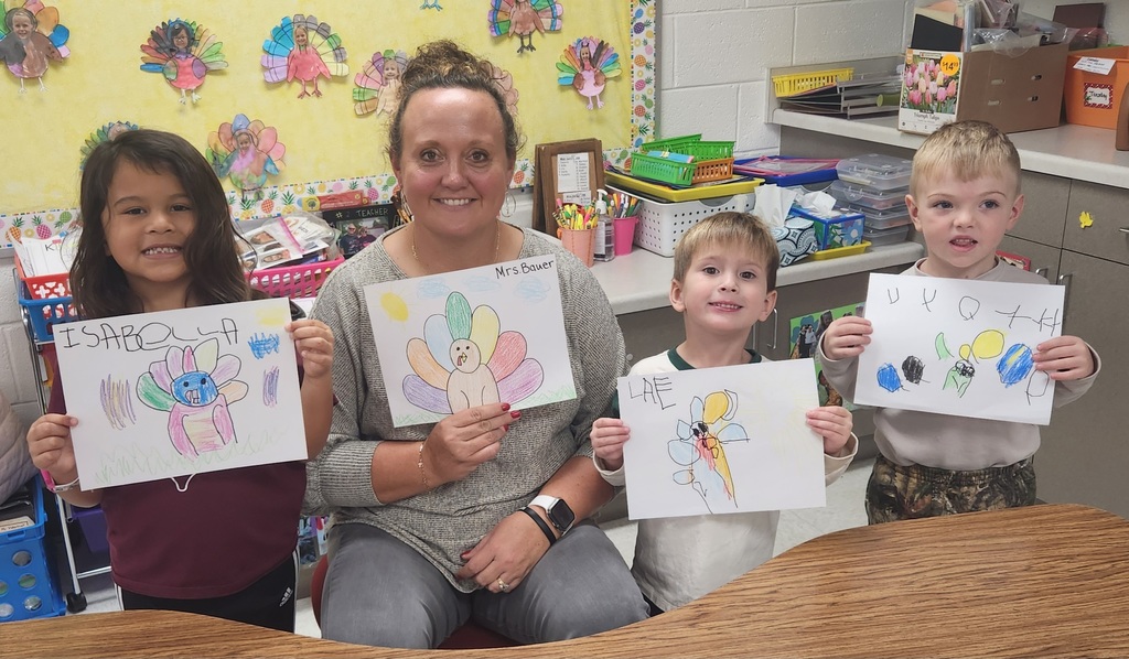Early elementary students with a teacher showing their directed drawing results.