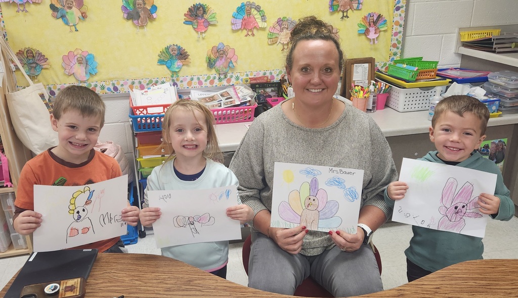 Early elementary students with a teacher showing their directed drawing results.