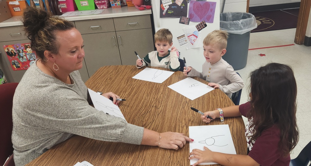 Early elementary students working with a teacher on a directed drawing. 