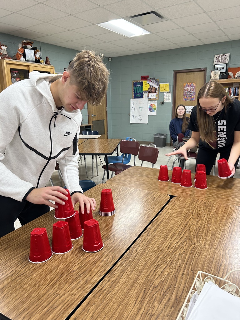 Two high school students cup stacking on tables.