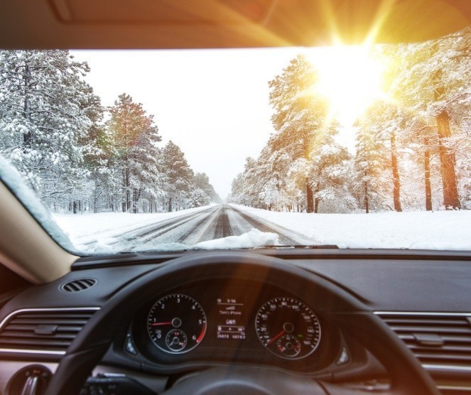 Image of a snowy road looking through a driver's windshield. 