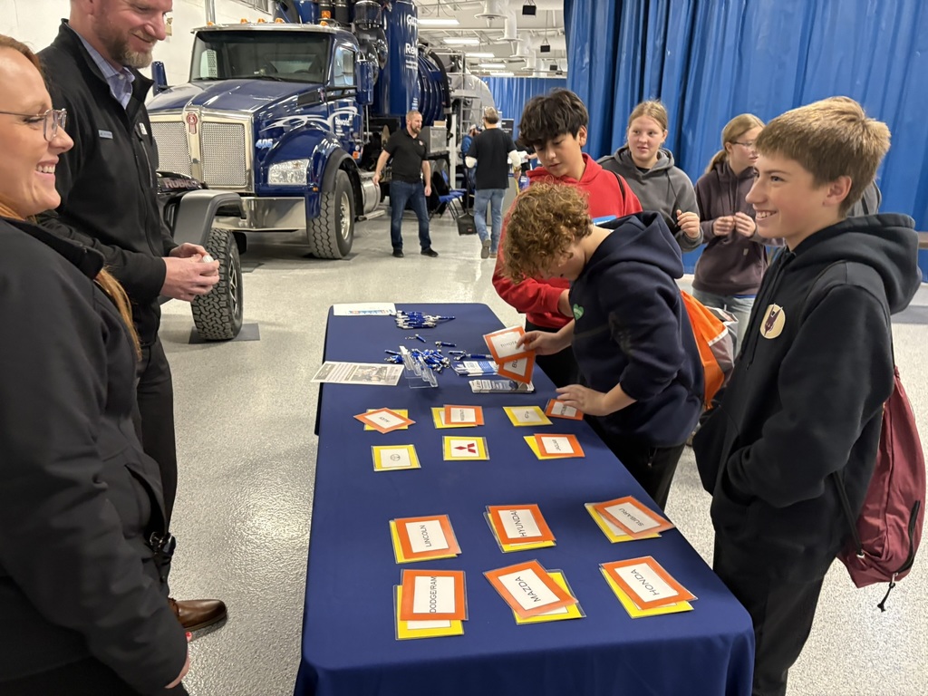 Middle school students at a table with information while attending a career expo.