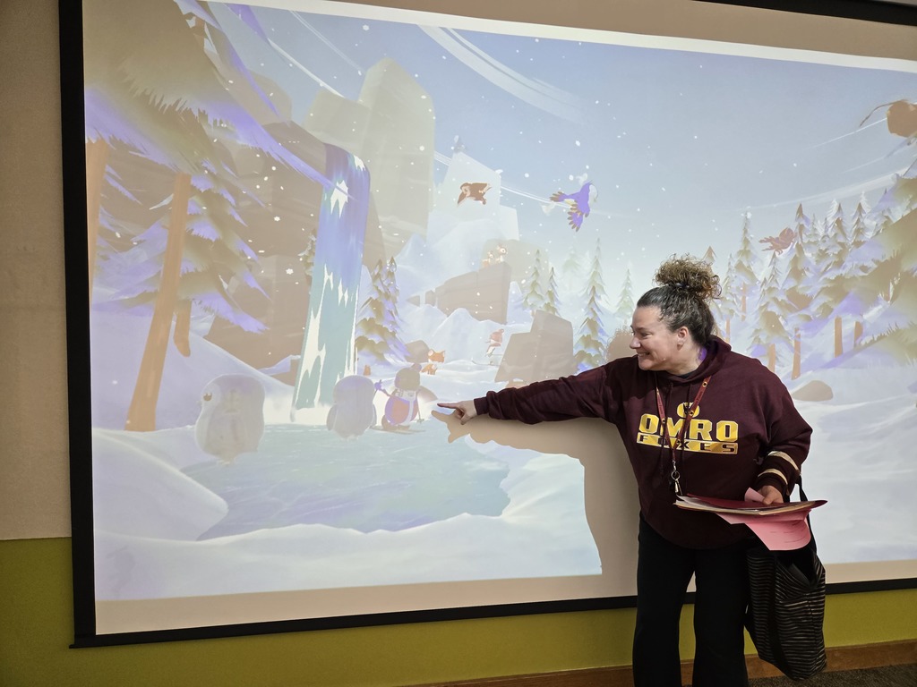 A teacher pointing at something on a screen.