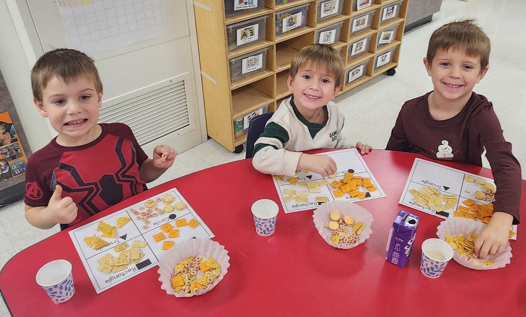 3 young elementary students, sitting at a table, sorting snacks by their shape.