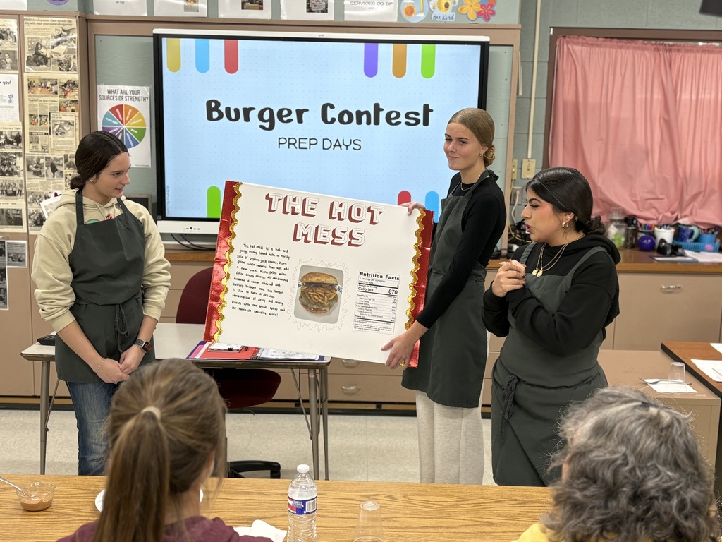 Three high school students presenting a poster in front of a class.
