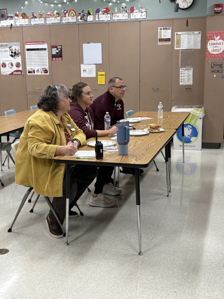 Three adults sitting at a a table, acting as judges in a burger creation contest.
