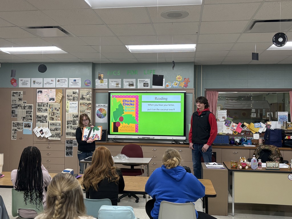 Two high school students presenting and reading a book aloud.