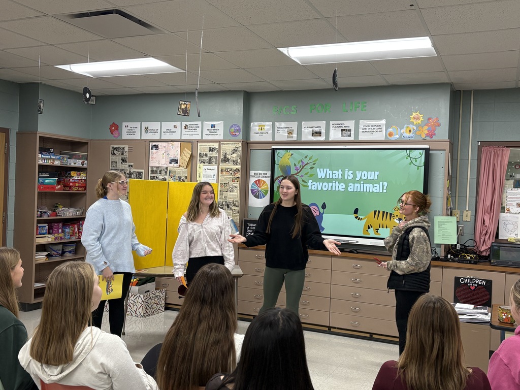 Four high school students presenting in front of a class.
