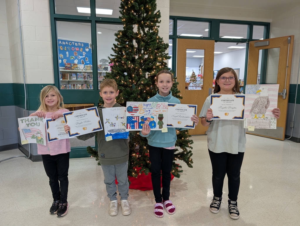 4 elementary students holding their posters in front of them. 
