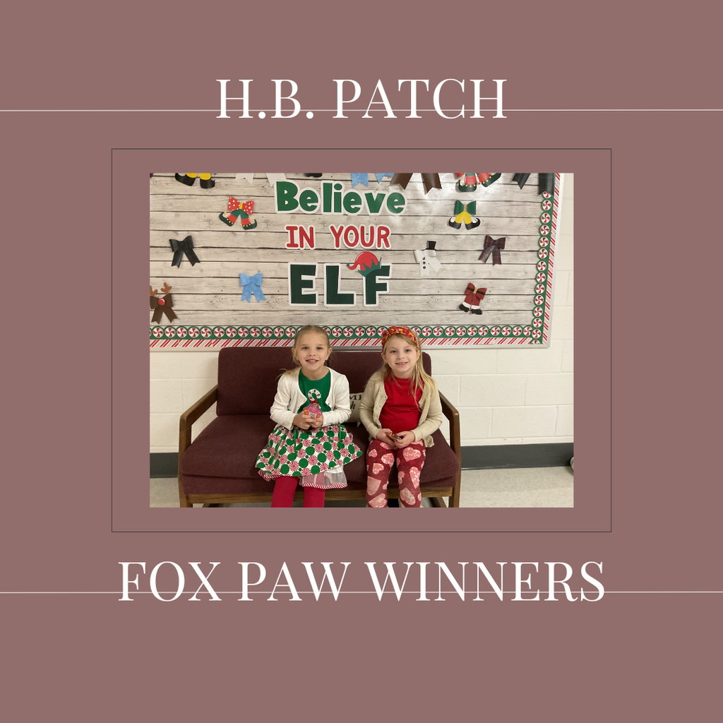 A couple of early elementary students standing in front of a bulletin board. 