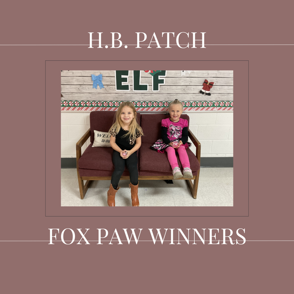 A couple of early elementary students standing in front of a bulletin board. 