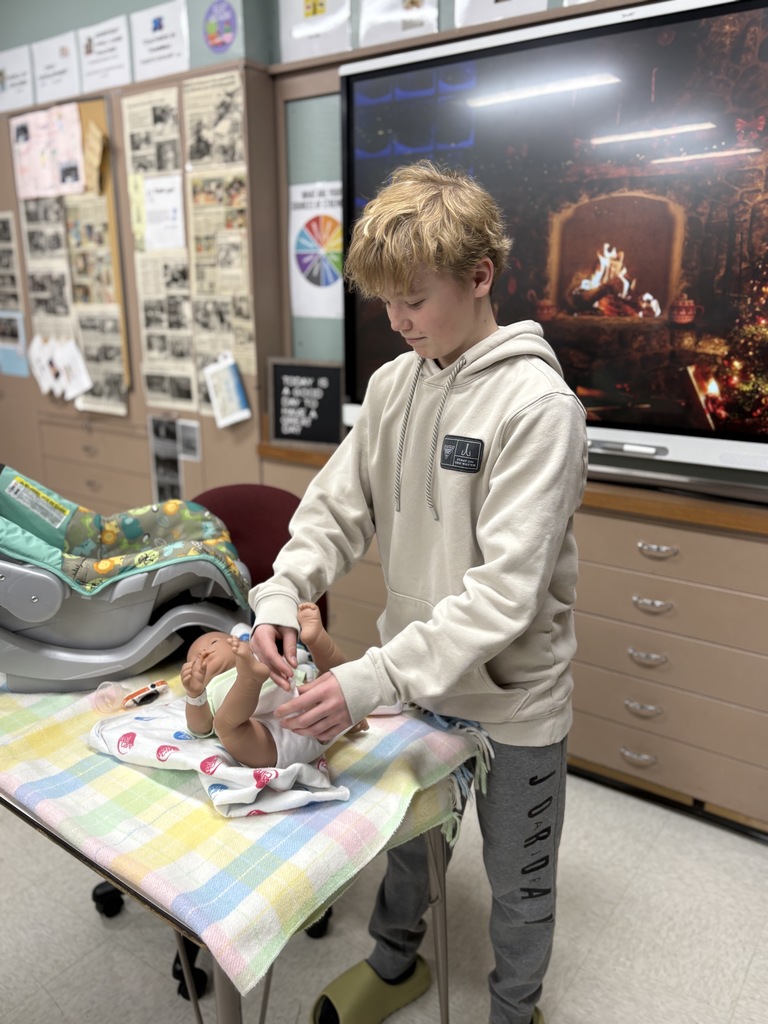 Middle school student "changing the diaper" on a baby simulator.