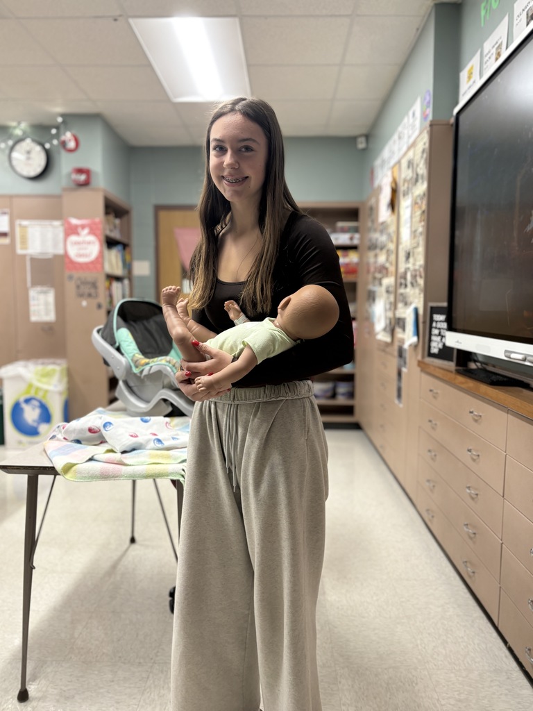 Middle school student holding a baby simulator.