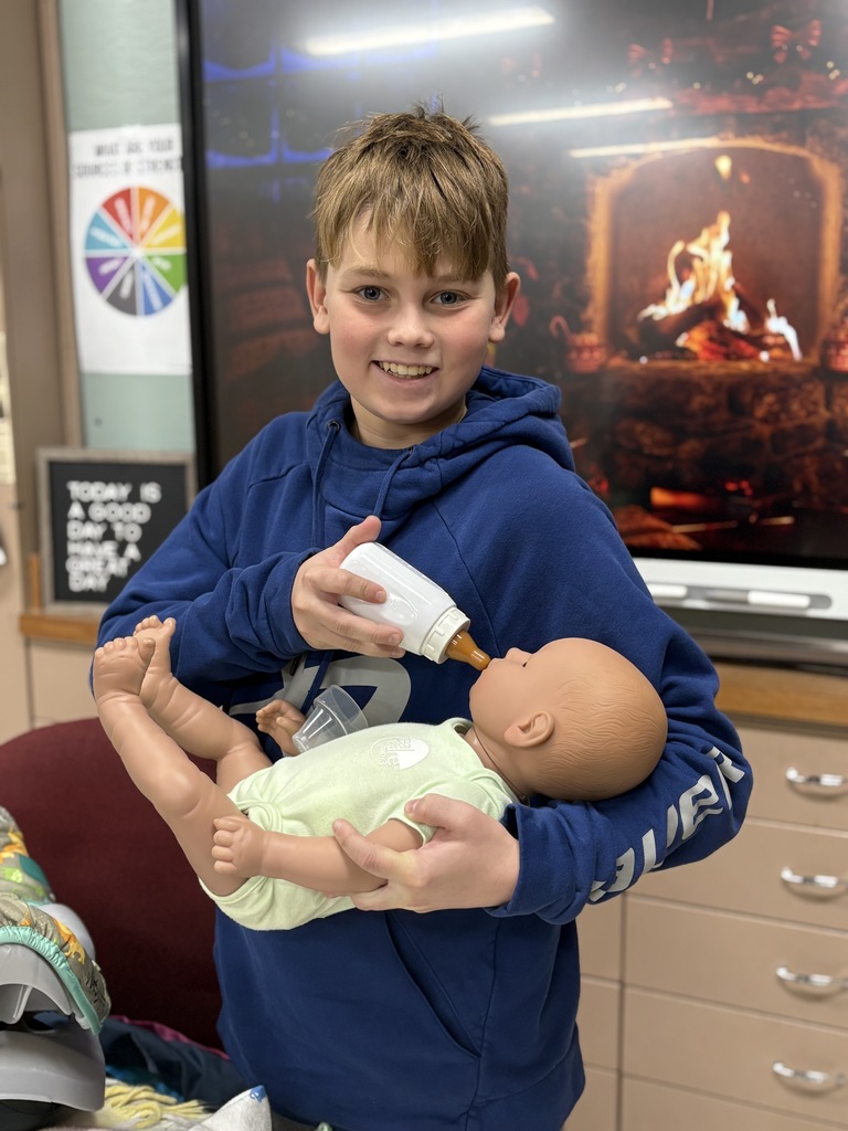 Middle school student holding and "feeding" a baby simulator.