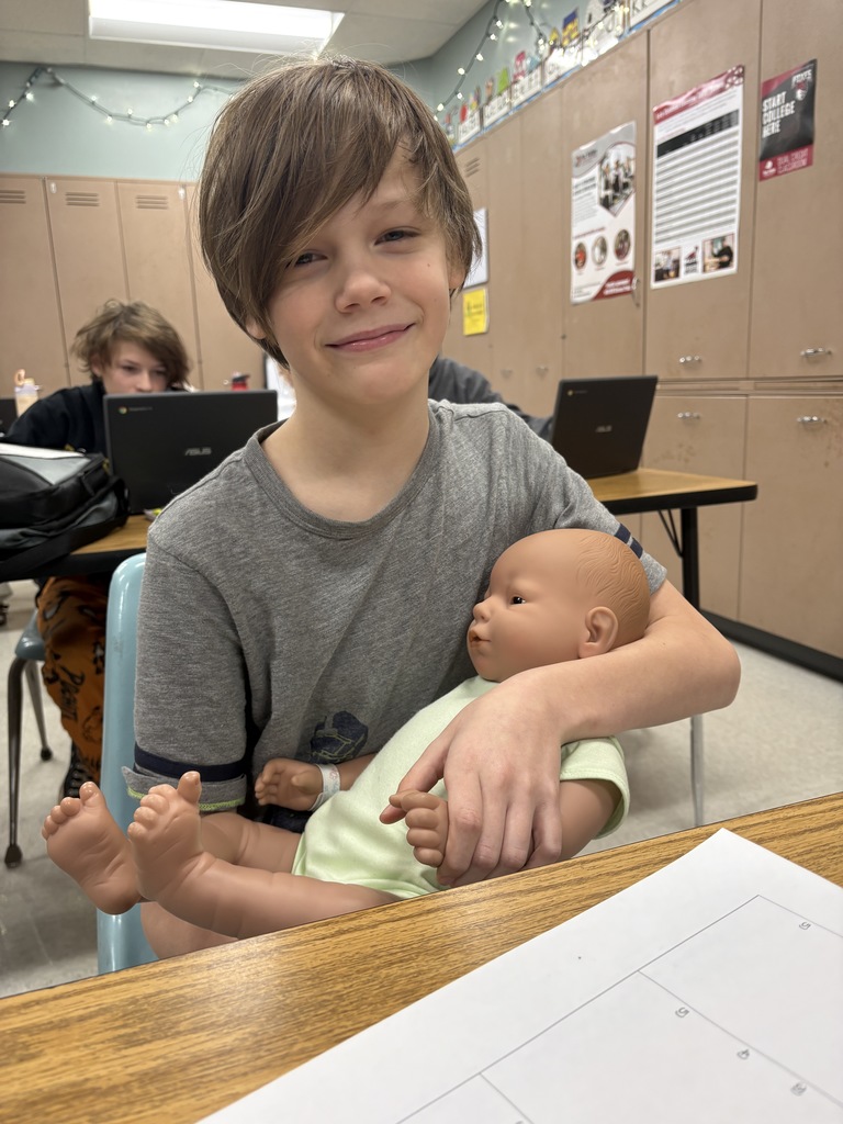 Middle school student holding a "baby simulator".