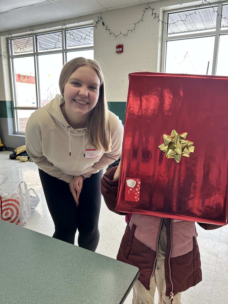 A high school student with an elementary student, holding a box in front of her face, standing together.