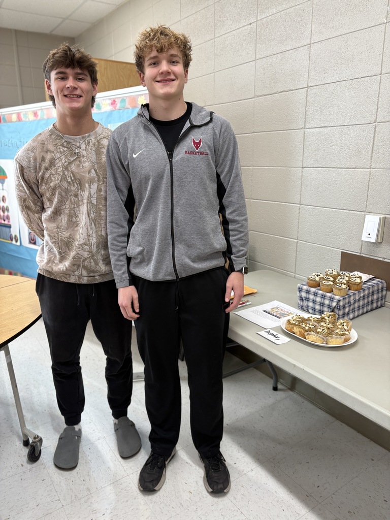 Two high school students standing near a cupcake display.