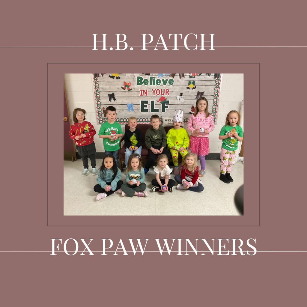 A group of early elementary students standing in front of a bulletin  board.