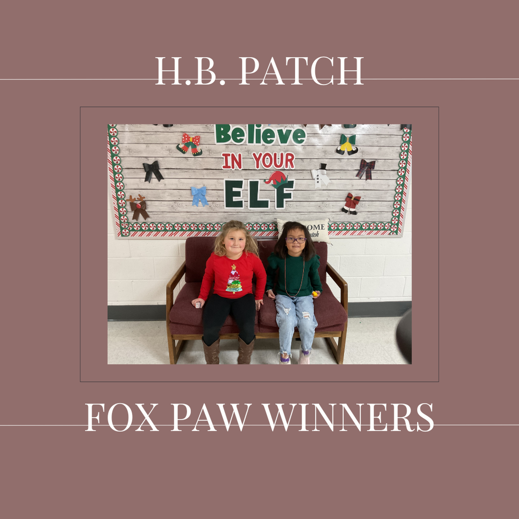 A couple of early elementary students standing in front of a bulletin board. 