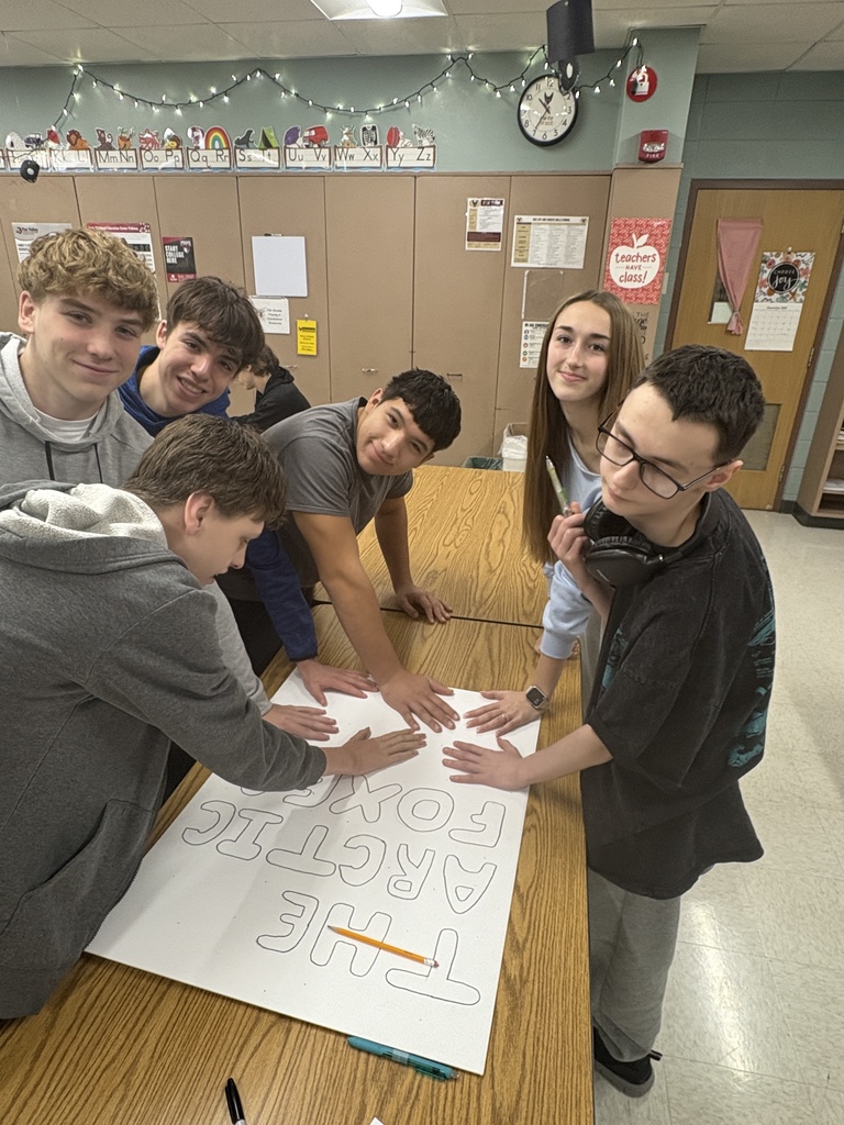 High school students gathered around a sign they are making.