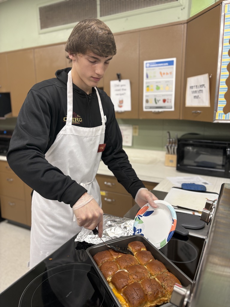 High school student working with food prep, taking rolls out of a baking pan.