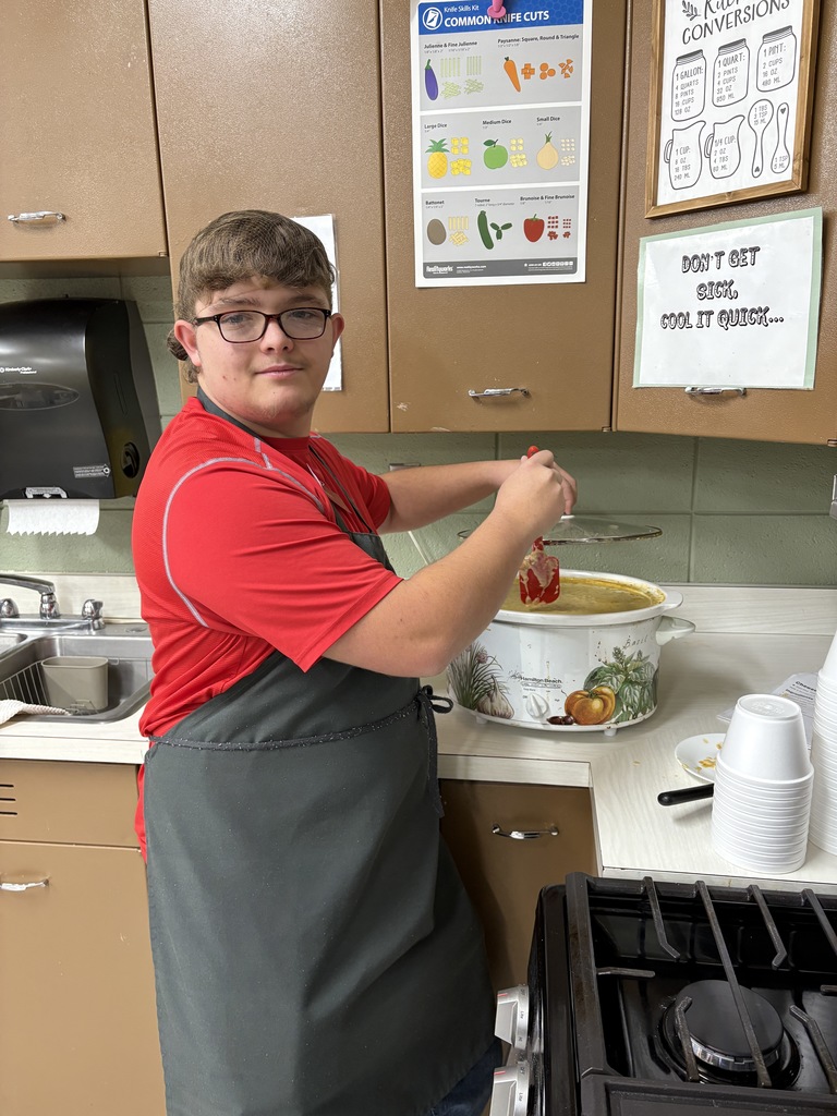 High school student stirring soup in a crock pot.