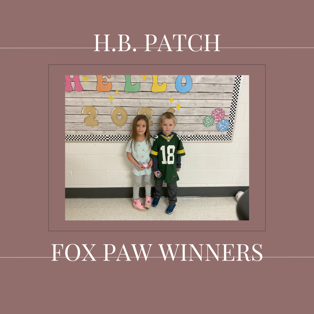 A couple of early elementary students standing in front of a bulletin board.