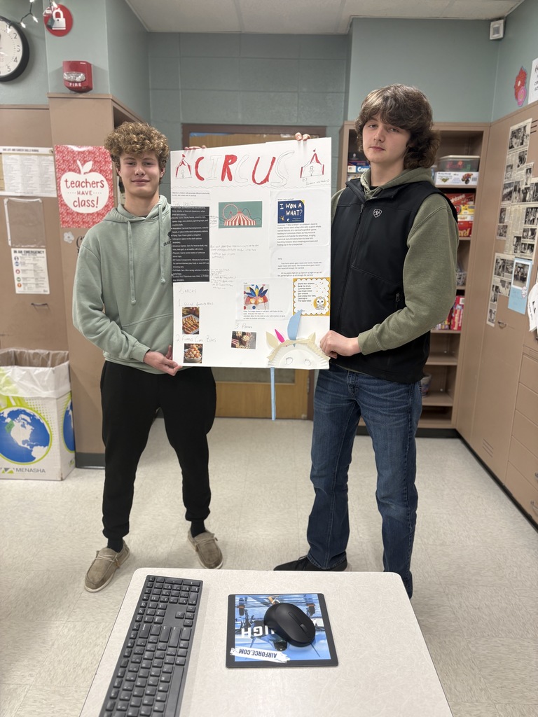 Two high school students hold a poster detailing their lesson plan about the circus.