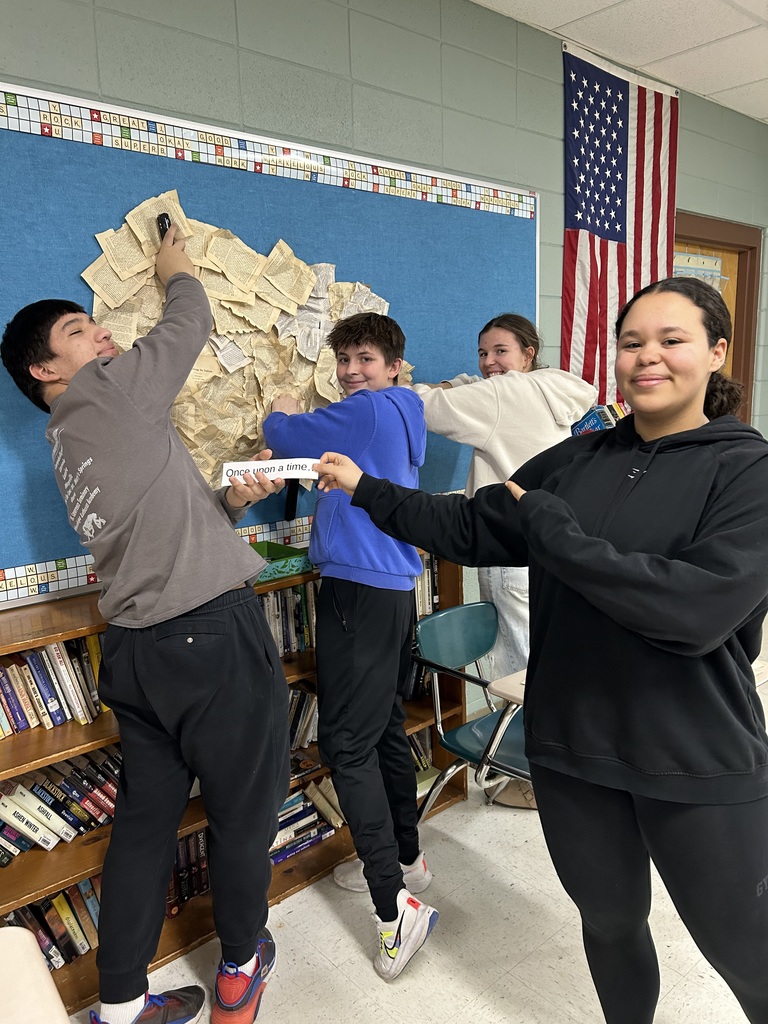 4 high school students creating a bulletin board for a classroom.
