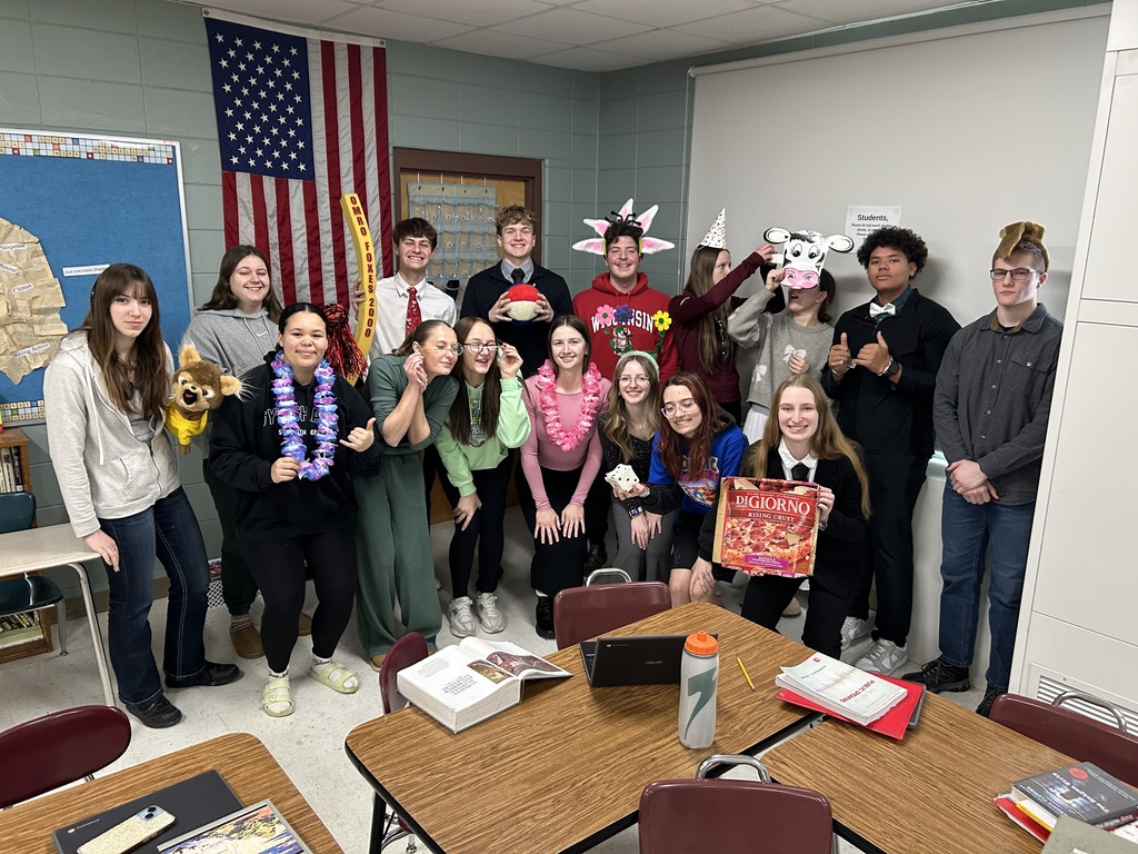 A group of high school students posing together with funny objects.
