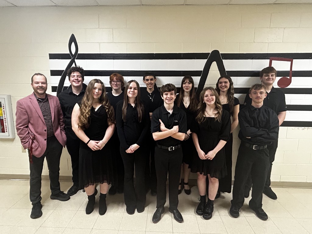 A group of high school students wearing all black concert attire, along with their director.