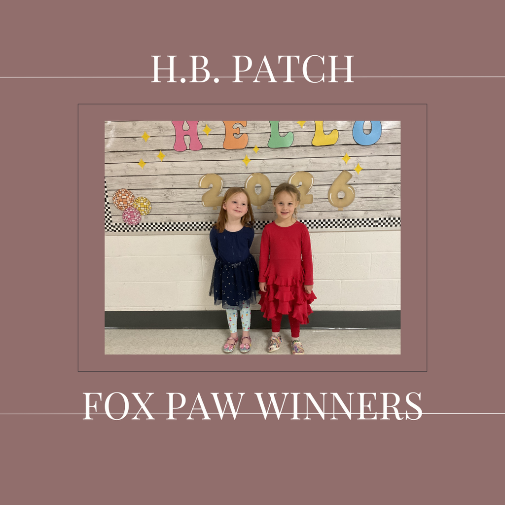 A couple of early elementary students standing in front of a bulletin board.