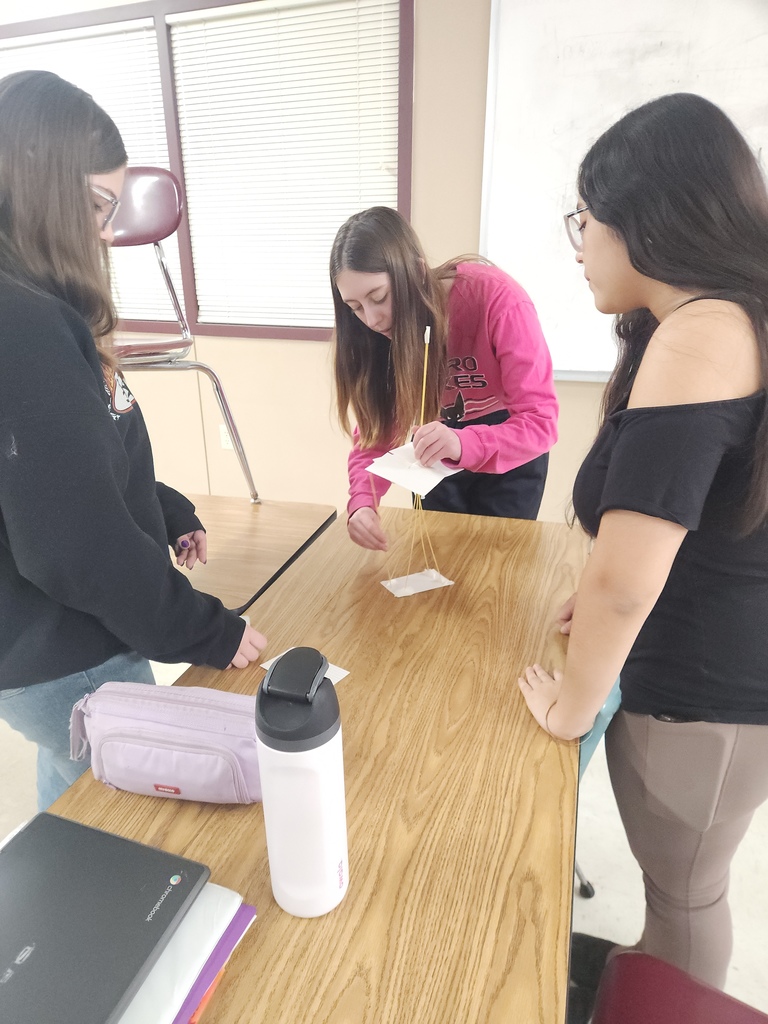 A group of high school students who are gathered in a group building a STEAM activity.