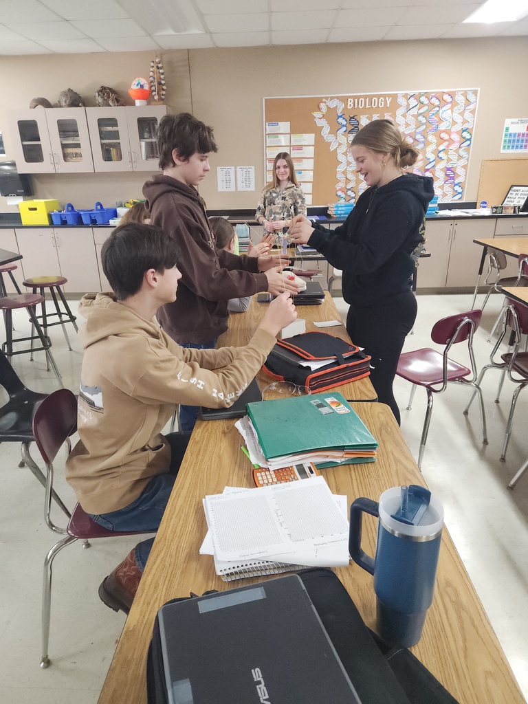 A group of high school students who are gathered in a group building a STEAM activity.